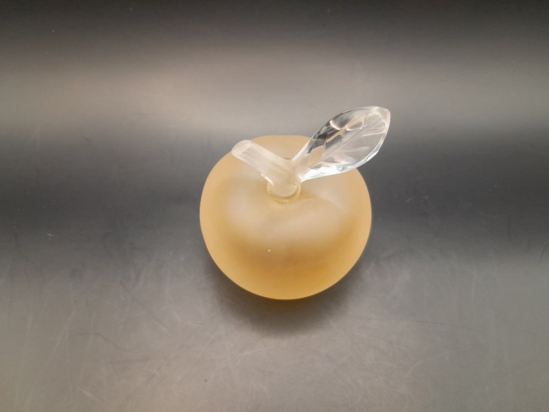 May include: A frosted glass apple shaped bottle with a clear glass stem and leaf.