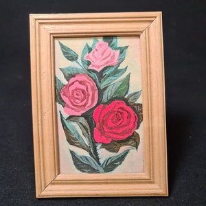 Un pequeño cuadro decorativo de flores de rosas. El cuadro está realizado sobre cartón y en un marco de madera.