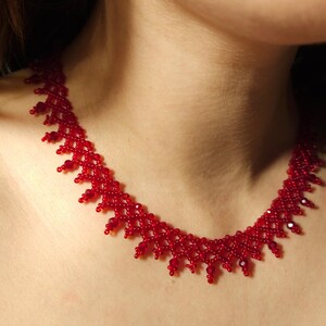 May include: A vibrant red beaded necklace. The necklace features a delicate, intricate design with small, round beads and larger, faceted beads. The necklace is a striking piece of jewelry.