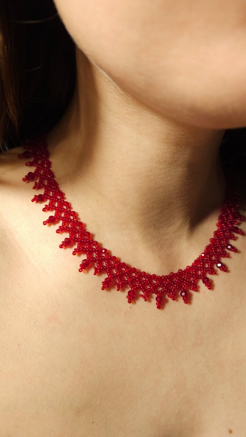 May include: A vibrant red beaded necklace. The necklace features a delicate, intricate design with small, round beads and larger, faceted beads. The necklace is a striking piece of jewelry.