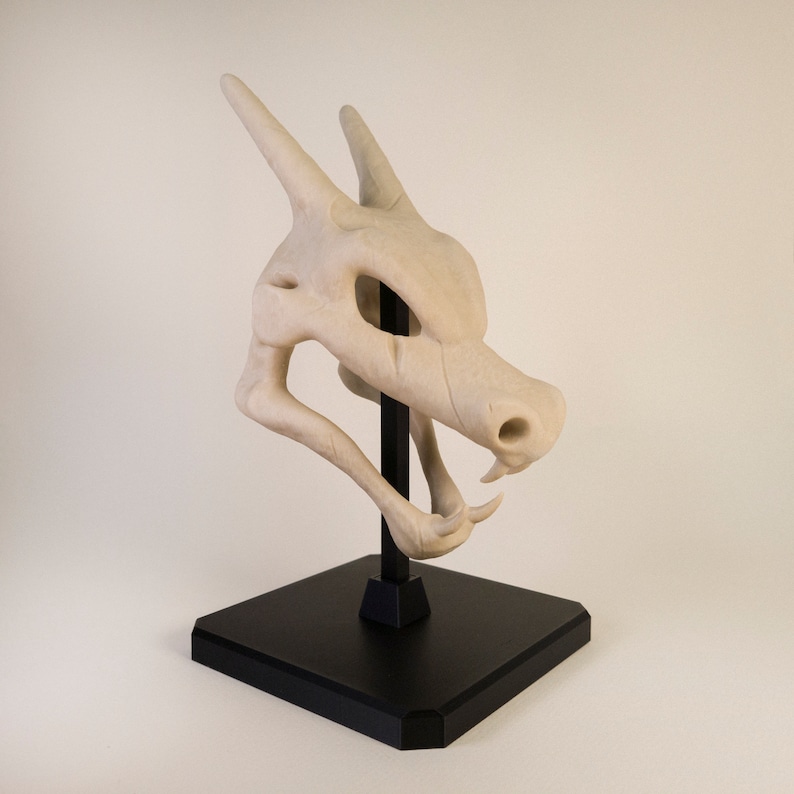 Figurine Crane de Dracaufeu (Pokémon) réaliste. Couleur os et monté sur socle et tige noir. Impression 3D