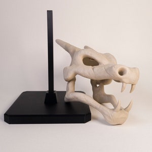 Figurine Crane de Dracaufeu (Pokémon) réaliste. Couleur os et monté sur socle et tige noir. Impression 3D