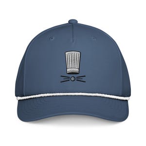 May include: A navy blue baseball cap with a white rope detail. The cap has an embroidered chef's hat and whiskers design in white and black. A fashionable accessory for those who enjoy cooking.