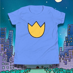 May include: A pale blue t-shirt with a yellow crown emblem outlined in black. The image includes a cartoon cityscape with buildings and a night sky, creating a playful backdrop.