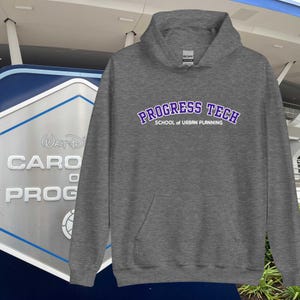 Puede incluir: Una sudadera con capucha gris con el texto "PROGRESS TECH SCHOOL of URBAN PLANNING" en letras moradas. La sudadera tiene un bolsillo delantero y una capucha con cordón. El fondo incluye un letrero y elementos arquitectónicos.