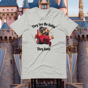 May include: A gray t-shirt with a cartoon image of a character driving a red car. The text "They See Me Rollin' They Hatin'" is printed on the shirt.
