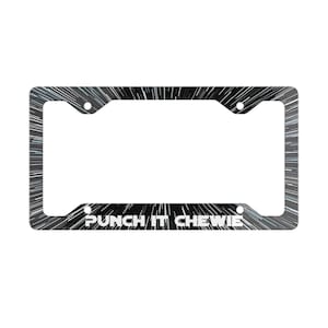 May include: A rectangular license plate frame featuring a black background with white radial light streaks resembling hyperspace travel. The text PUNCH IT CHEWIE is printed in white capital letters along the bottom edge of the frame.