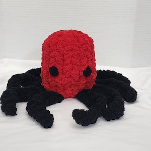 Könnte beinhalten: Ein handgefertigter Plüsch-Oktopus mit einem leuchtend roten Kopf und schwarzen Tentakeln. Der Oktopus hat zwei schwarze Augen und besteht aus einem weichen, strukturierten Material. Ein kuscheliges Spielzeug für Kinder und Erwachsene.