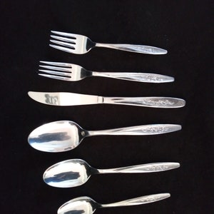 May include: A set of five silver-toned utensils, including two forks, a knife, and two spoons. The utensils have a floral design etched into the handles.