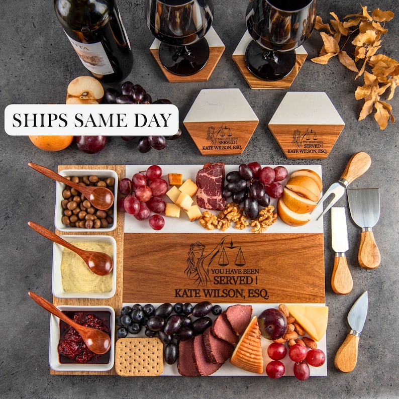 May include: A rectangular wooden and white serving board engraved with the text YOU HAVE BEEN SERVED! KATE WILSON, ESQ. and a scales of justice icon, accompanied by three white bowls with wooden spoons, cheese, fruit, crackers, and metal cheese knives.