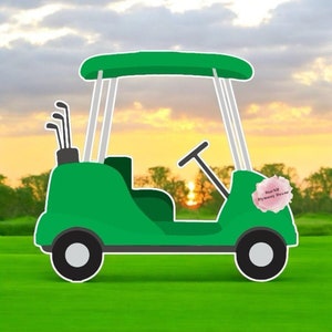 May include: A green golf cart with a white roof and white wheels. The golf cart has a golf bag with clubs in the back. The golf cart is on a green grass field with a sunset in the background. The golf cart has a pink flower sticker on the side that says 