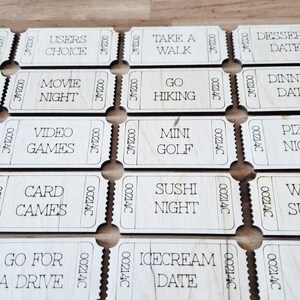 May include: A collection of wooden date night tickets, each engraved with a different activity idea such as "Take a Walk" and "Mini Golf." The tickets are rectangular with a serial number and a perforated edge for easy separation.
