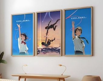 May include: Three framed movie posters with a blue background and the text "Your Name." in white. The posters feature characters from the anime film "Your Name." The posters are hanging on a white wall.