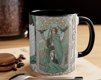 May include: A black and white ceramic mug with a black handle. The mug features a colorful illustration of a character from the anime Attack on Titan. The character is standing in a green cloak with a sword in their hand. The background is a stylized art nouveau design with birds and a crest.