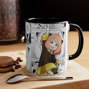 May include: White ceramic mug with a black interior and handle. The mug features a manga-style illustration of a character with pink hair and a brown dress. The background includes manga panels and the word "HEH."