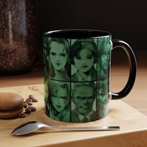 May include: A black-handled coffee mug with a green and black design. The mug features a grid of portraits in shades of green. The interior of the mug is black. A spoon and a pastry are in the foreground.
