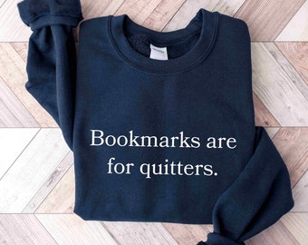 May include: Navy blue sweatshirt with the text "Bookmarks are for quitters" in white. The sweatshirt is made of a soft material and is perfect for book lovers.