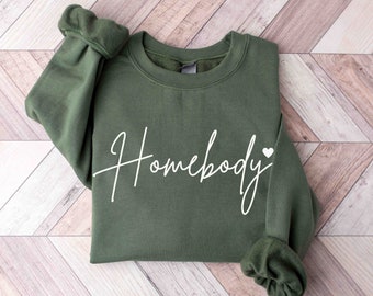 May include: A green sweatshirt with the text "Homebody" in white cursive lettering and a small white heart.