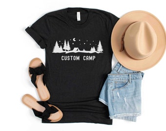 May include: Black t-shirt with a white graphic of a campsite with trees, a tent, and stars. The text "CUSTOM CAMP" is printed below the graphic.