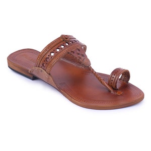Pu&ograve; includere: Sandalo in pelle marrone con un cinturino a infradito e una fascia sulla parte superiore del piede. Il sandalo presenta motivi decorativi traforati e una suola strutturata. Il sandalo &egrave; progettato per il comfort e lo stile.