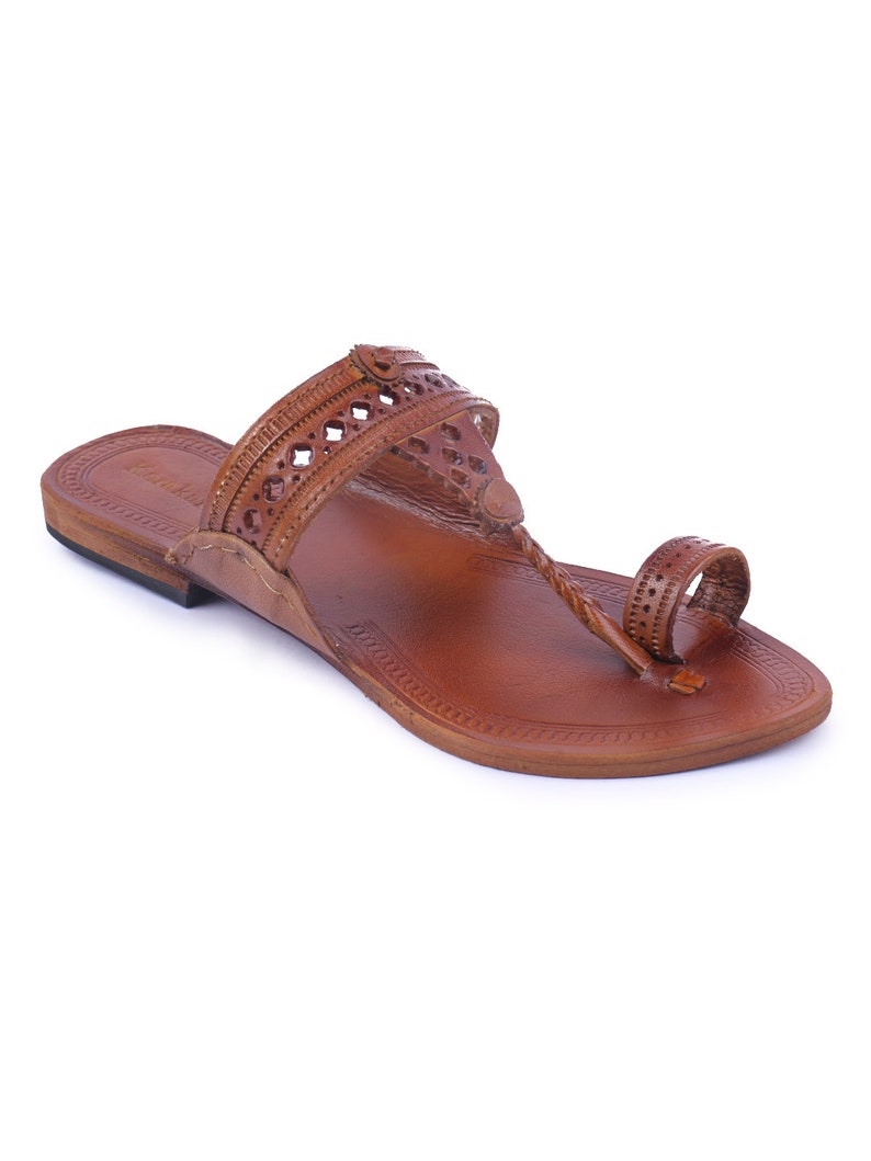 Pu&ograve; includere: Sandalo in pelle marrone con un cinturino a infradito e una fascia sulla parte superiore del piede. Il sandalo presenta motivi decorativi traforati e una suola strutturata. Il sandalo &egrave; progettato per il comfort e lo stile.