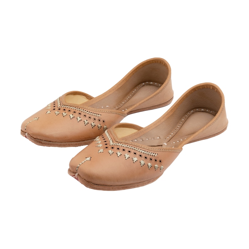 May include: A pair of tan leather shoes with intricate embroidery and decorative stitching. The shoes have a pointed toe and a low heel.