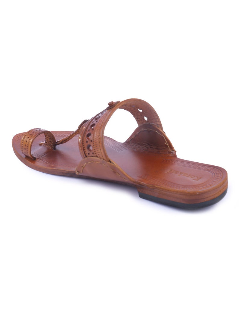 Pu&ograve; includere: Sandalo in pelle marrone con anello per le dita e cinturino sulla parte superiore del piede. Il sandalo presenta intagli decorativi e una suola piatta. La pelle sembra usurata e il sandalo &egrave; progettato per il comfort e lo stile.