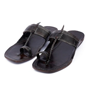 May include: A pair of black leather sandals with a toe loop and a strap across the top of the foot.