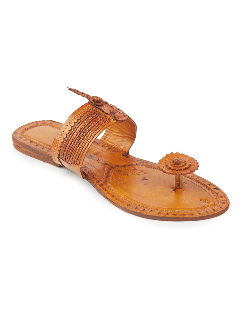 May include: A pair of brown leather sandals with intricate floral designs and a decorative flower embellishment on the toe strap.