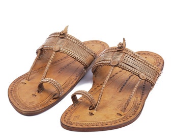 May include: A pair of brown leather sandals with intricate designs and braided straps. The sandals have a pointed toe and a flat sole.
