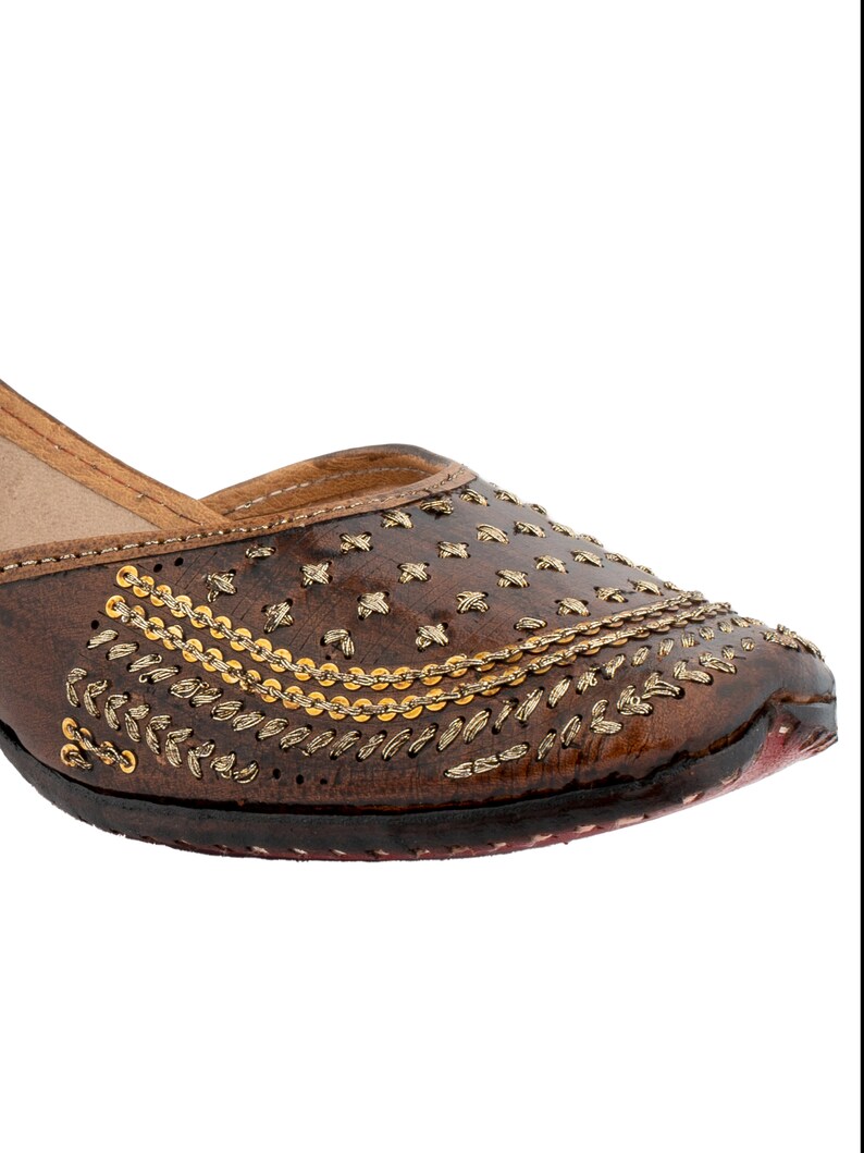 May include: Brown leather flat shoes with gold embroidery and embellishments.