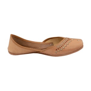 May include: A pair of tan leather shoes with intricate cutouts and gold accents. The shoes have a pointed toe and a low heel.