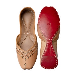May include: A pair of tan leather shoes with intricate embroidery and a red leather sole. The shoes have a pointed toe and a low heel.