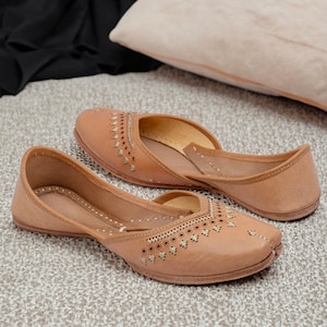 May include: A pair of tan leather shoes with intricate cut-out designs and gold embellishments. The shoes have a pointed toe and a low heel.