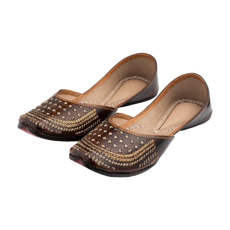 May include: A pair of brown leather shoes with gold embellishments. The shoes have a pointed toe and a low heel.
