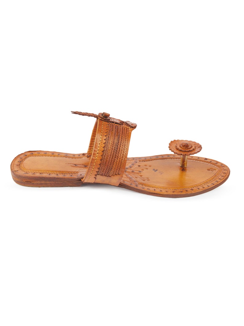 May include: A pair of brown leather sandals with intricate floral designs and a decorative flower embellishment on the toe strap.
