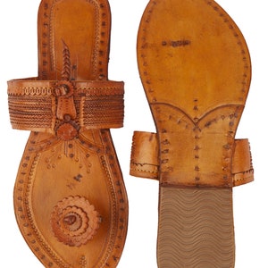 May include: A pair of brown leather sandals with intricate stitching and a floral design. The sandals have a pointed toe and a flat sole.