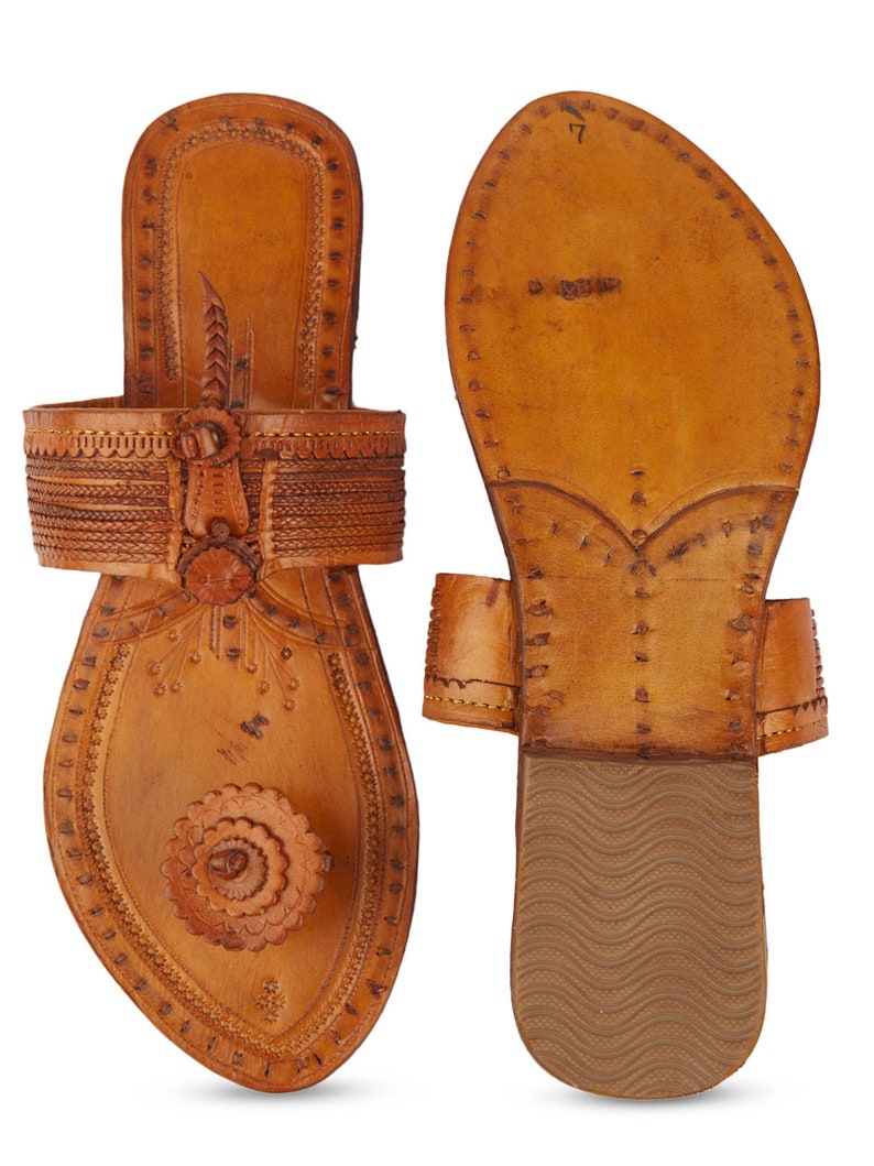 May include: A pair of brown leather sandals with intricate stitching and a floral design. The sandals have a pointed toe and a flat sole.