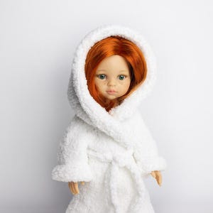 May include: A white plush bathrobe with a hood, worn by a doll with long red hair and blue eyes.