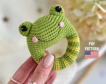 May include: Green crocheted frog rattle with yellow and green stripes. The frog has pink cheeks and black eyes.  PDF PATTERN.