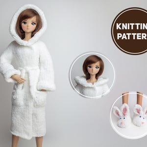 Puede incluir: Una bata blanca y esponjosa con capucha y cinturón de lazo. La bata la lleva puesta una muñeca con el pelo largo y castaño. La muñeca también lleva un par de zapatillas blancas de conejo.