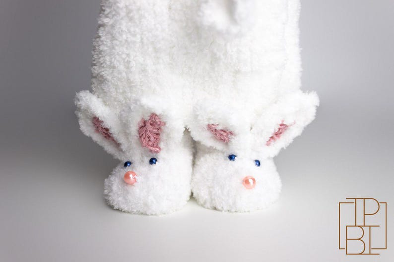 May include: White fuzzy bunny slippers with pink ears and blue eyes. The slippers have a fluffy texture and are perfect for keeping your feet warm.