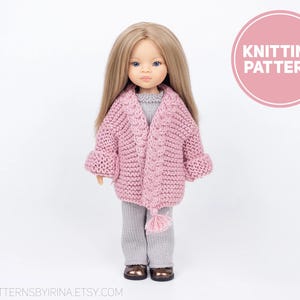 Puede incluir: Patrón de tejido de punto para un cárdigan rosa con un diseño de punto de cable y una borla. El cárdigan lo lleva una muñeca con el pelo rubio.