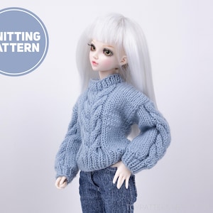 May include: A light blue knitted sweater with a cable knit pattern. The sweater has a high neck and long sleeves. The sweater is being worn by a doll with white hair.