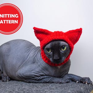 May include: A Sphynx cat wearing a bright red knitted hat with pointed ears. The cat has black fur and green eyes. The image includes a red circle with the words "KNITTING PATTERN" in white.