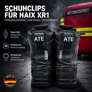 Op de afbeelding: Een paar zwarte leren laarzen met op maat gemaakte schoenclips met het label ATE op de hiellussen. De tekst op de afbeelding luidt SCHUHLCLIPS FÜR HAIX XR1, PERSONALISIERBAR, FUNKTIONAL, EINSATZBEREIT, Fester Halt, 3D Gedruckt en UV Bedruckt.