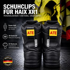 Könnte beinhalten: Ein Paar schwarze Lederstiefel mit leuchtend gelben, rechteckigen Clips an den hinteren Zuglaschen, die jeweils den Text ATE in roten Buchstaben zeigen. Die Stiefel haben weiße Gore-Tex-Etiketten und ein Made in Germany-Emblem.