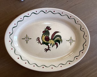 May include: A white oval serving platter with a green and red border. The center of the platter features a yellow, green, and red rooster illustration.