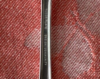 May include: Close-up of the back of a silver fork with the words "Tuco Plate Oneida Community" engraved on the handle.