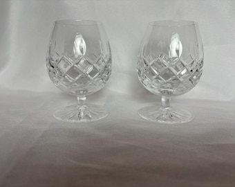 Puede incluir: Dos copas de brandy de cristal transparente con un diseño de cristal tallado.